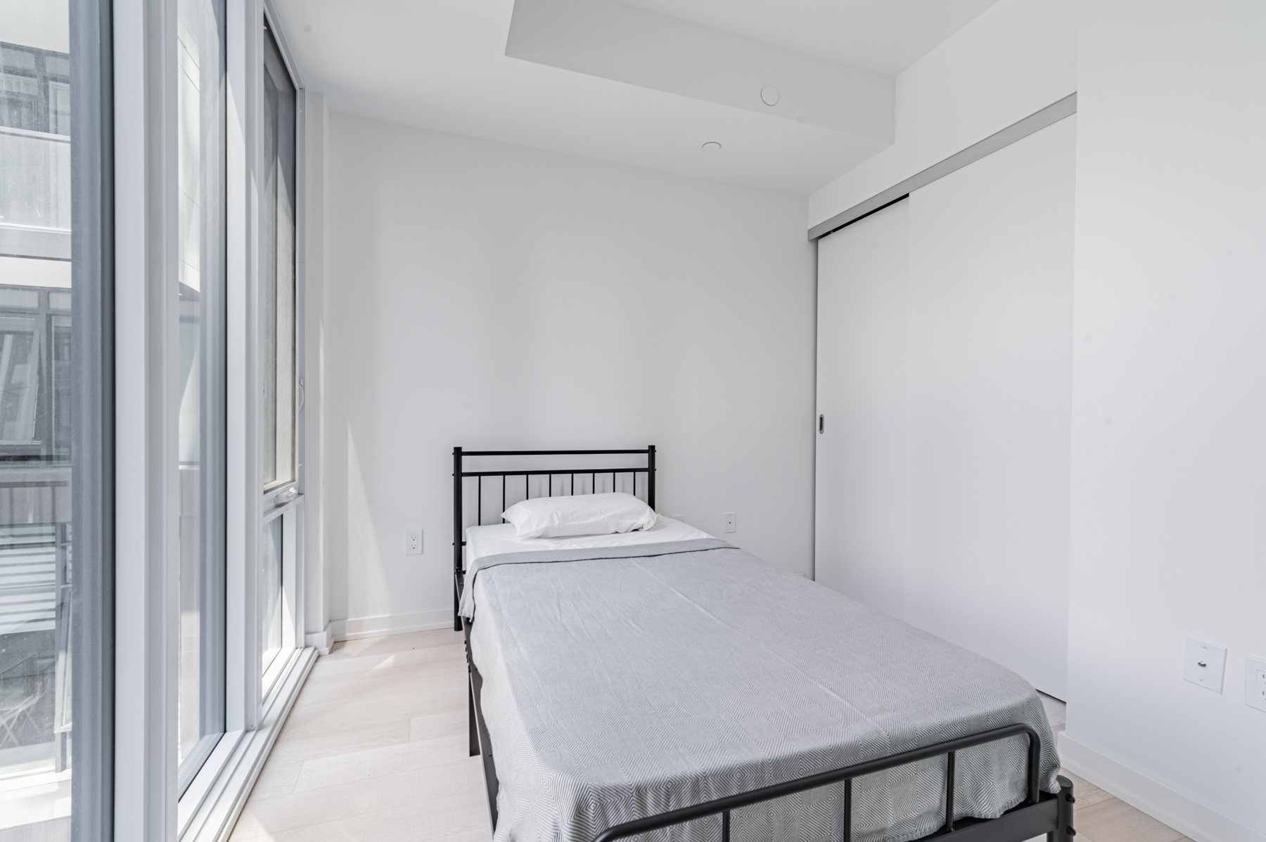 Condo bedroom with large gray sliding door closet.