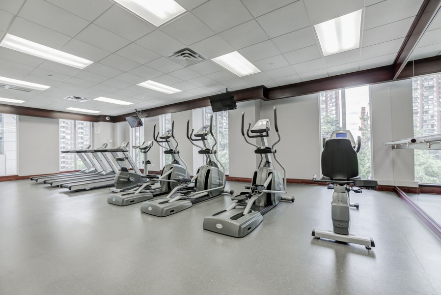 Condo gym with exercise bikes and treadmills with large windows.
