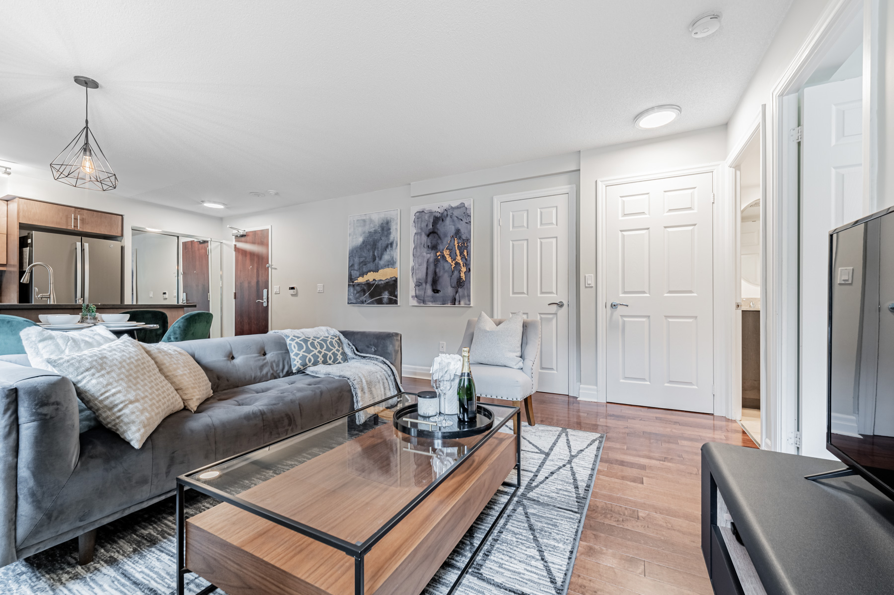 Large condo living room with gray sofa and glass table.