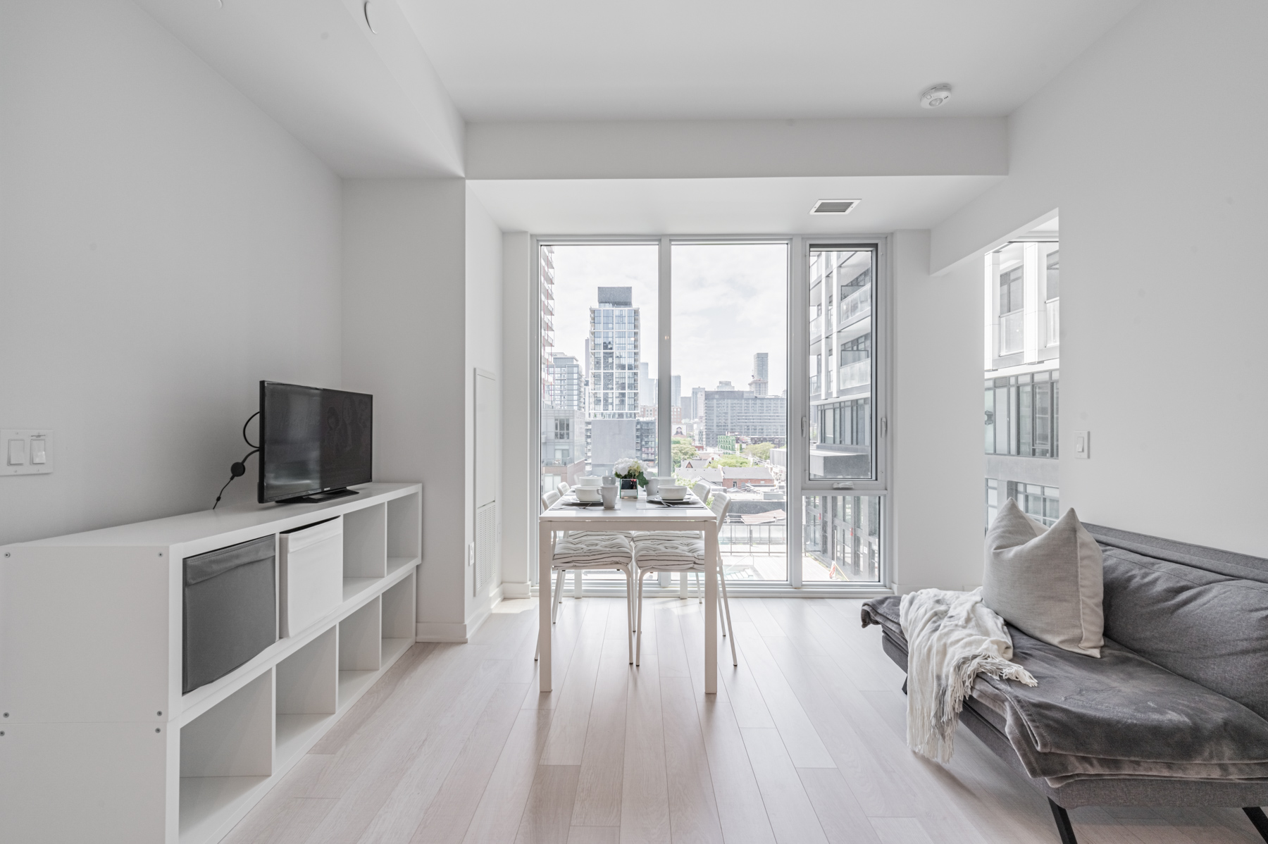 Condo unit with tall windows showing view of Toronto.