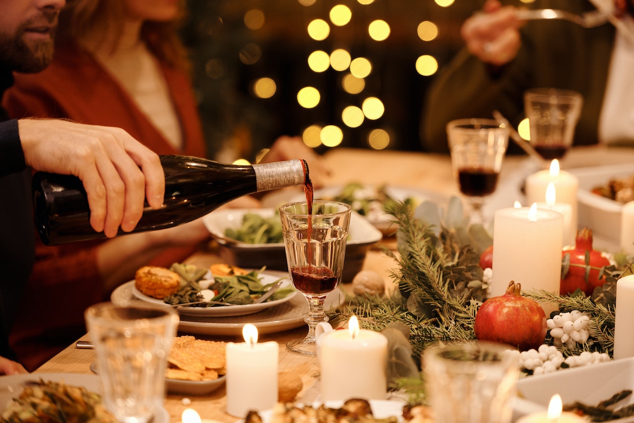 Person pouring wine into cup during fancy dinner.