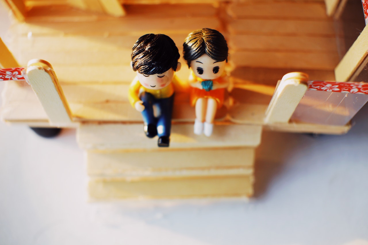 Male and female toy figures sitting on matchstick porch.