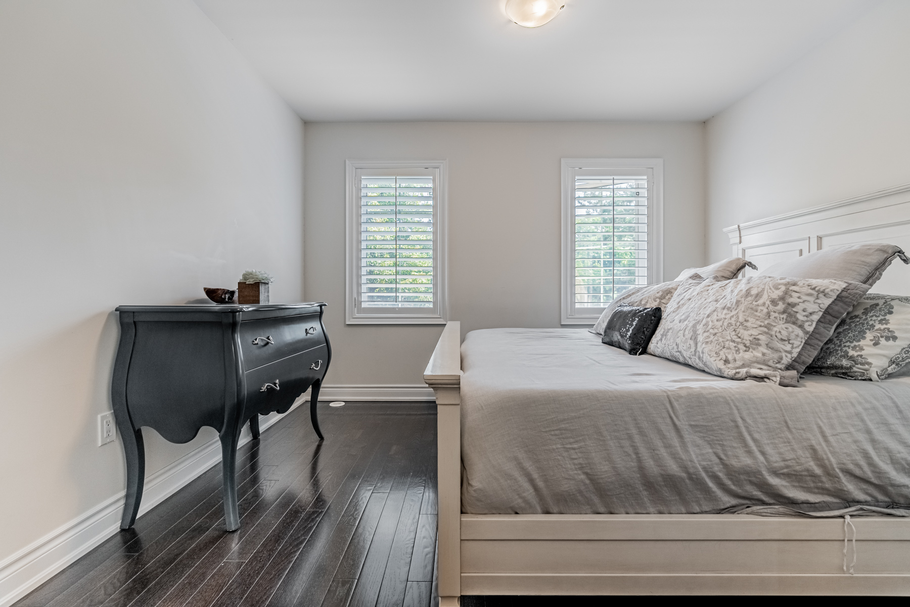 Bedroom with large bed and antique dresser.