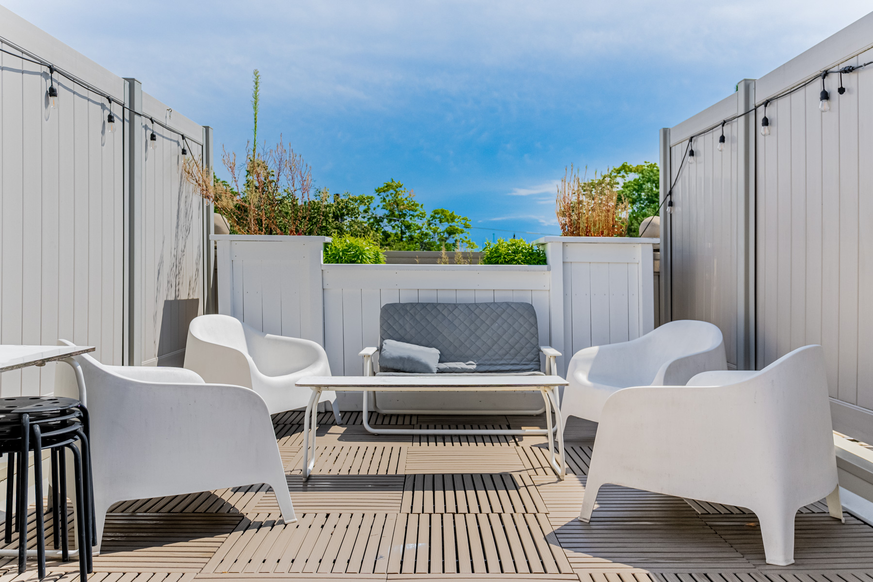 Rooftop terrace with several chairs and table.