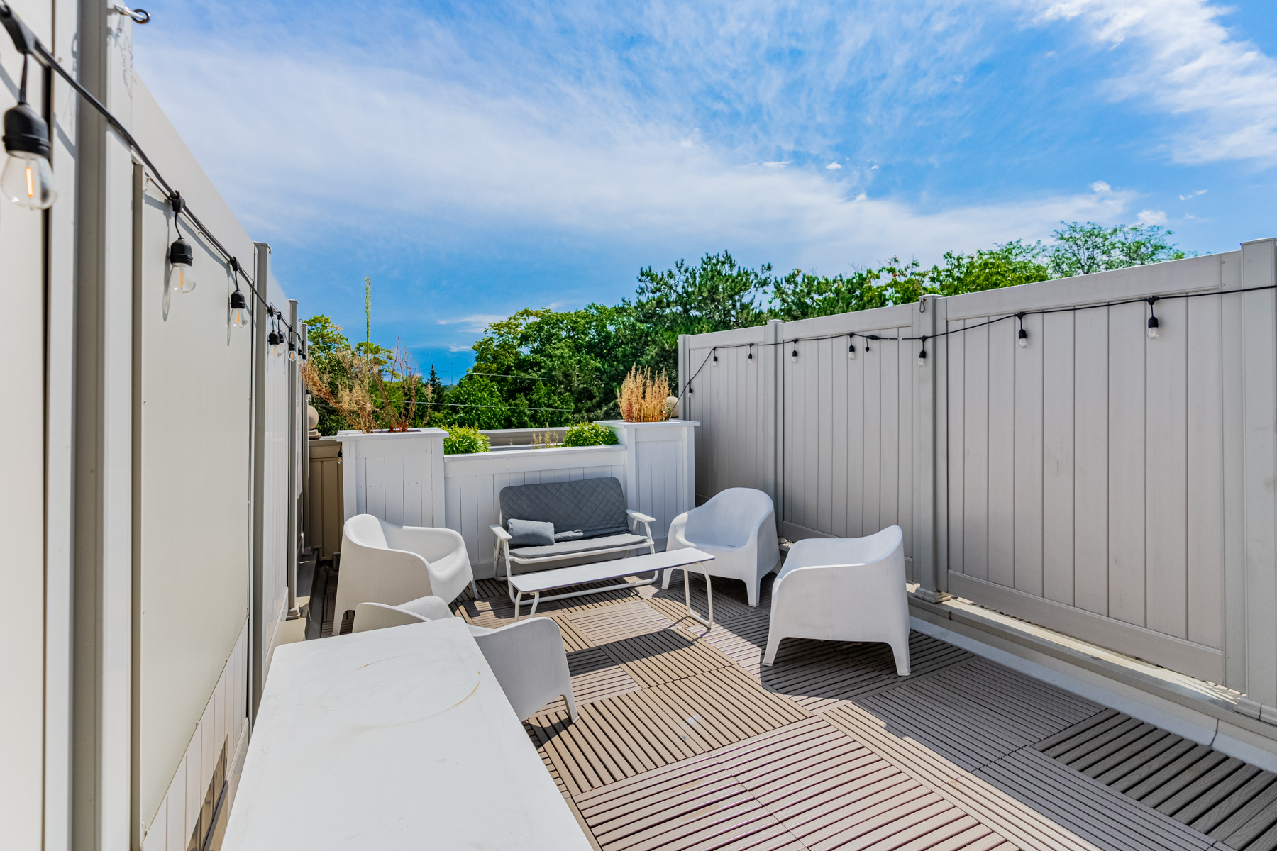 Rooftop terrace with table, stringed lights and furniture.