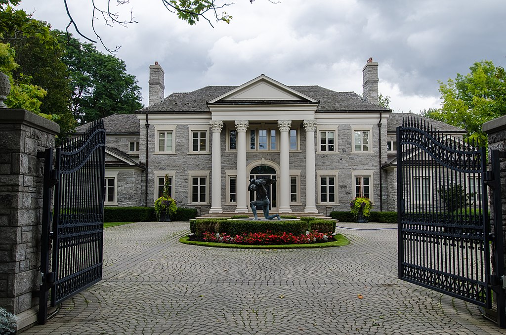 Large mansion with Atlas statue seen from gate. 