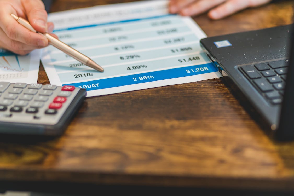 Close up of hand with pen pointing to paper with interest rates to show impact of rates on July 2023 market. 