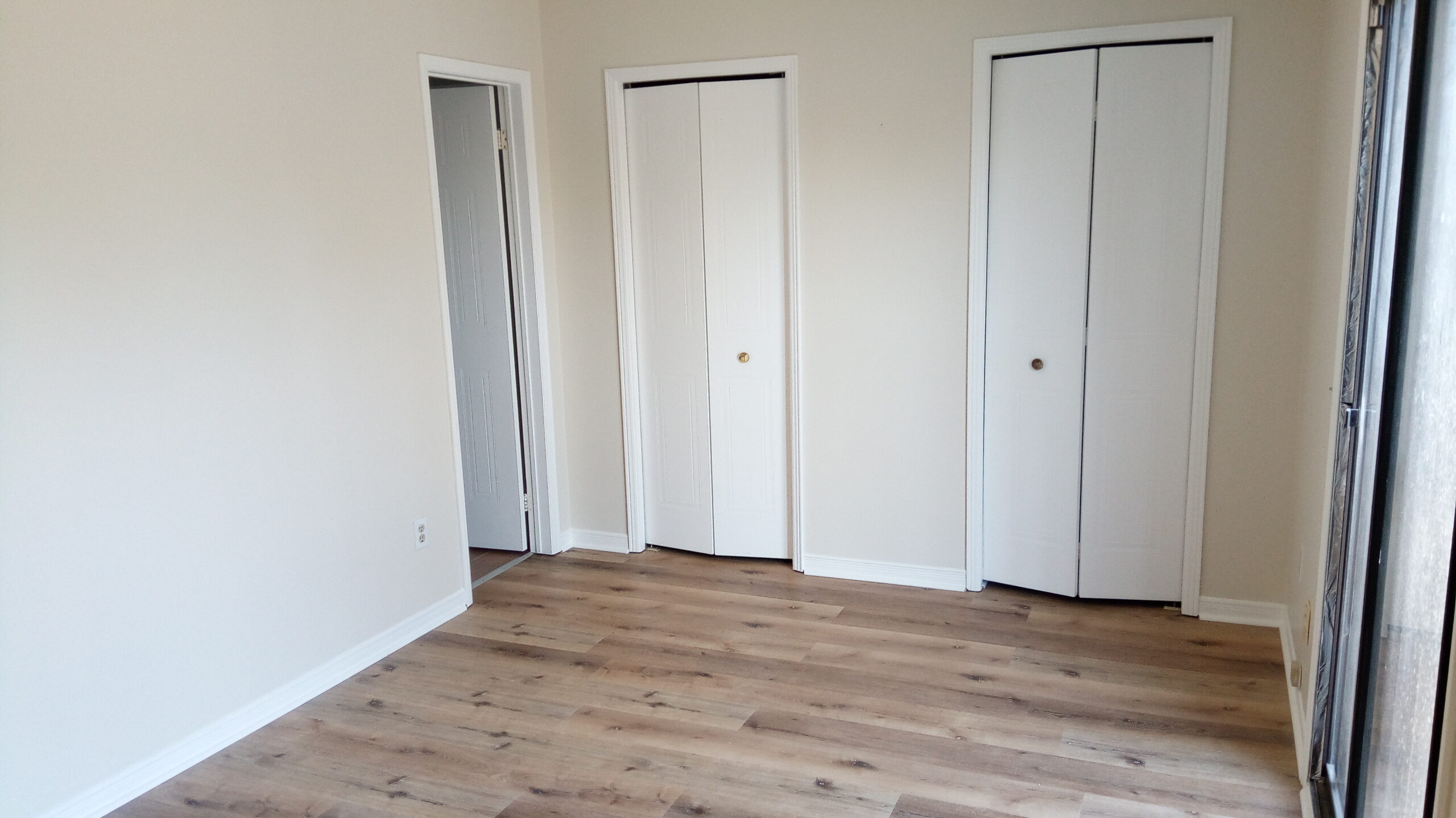 The bedroom sports smoky laminate floors and dual closets.Studio bedroom with dark laminate floors and two closets.