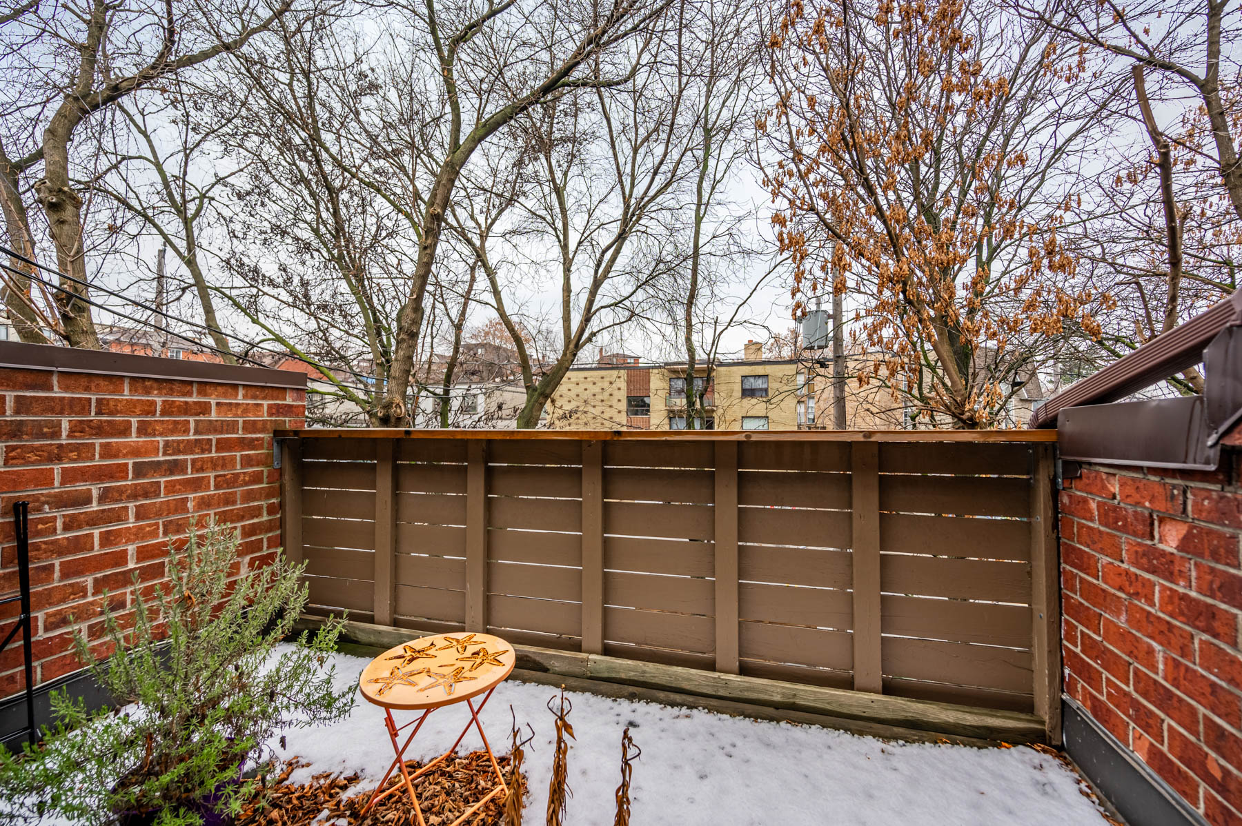 2133 Dufferin St – Second Floor Rental Unit E walk-out deck with red-brick wall and wood fence.