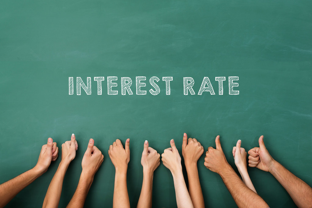 Image of green board with word "Interest Rate" and hands beneath.