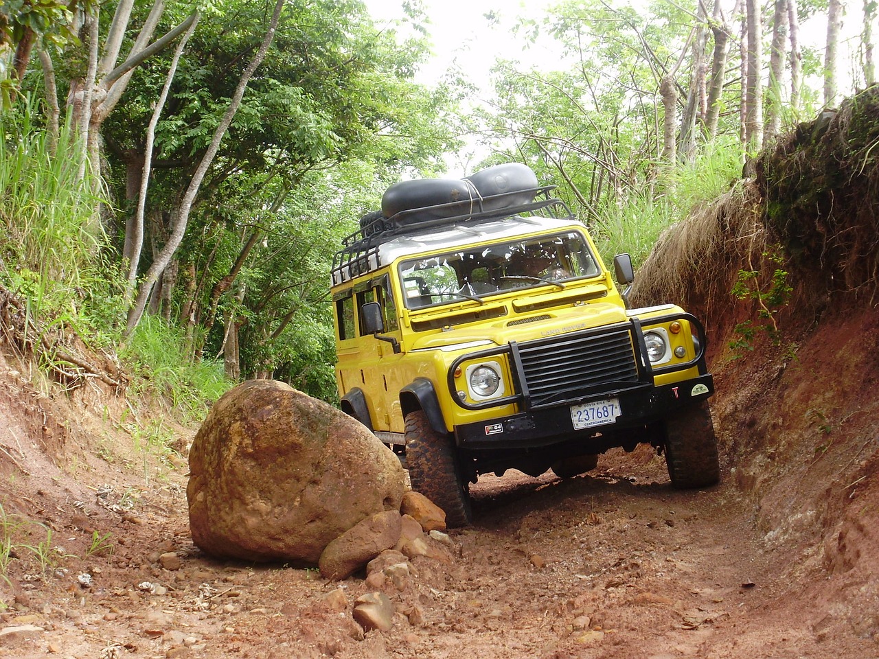 Yellow Land Rover avoiding boulder.