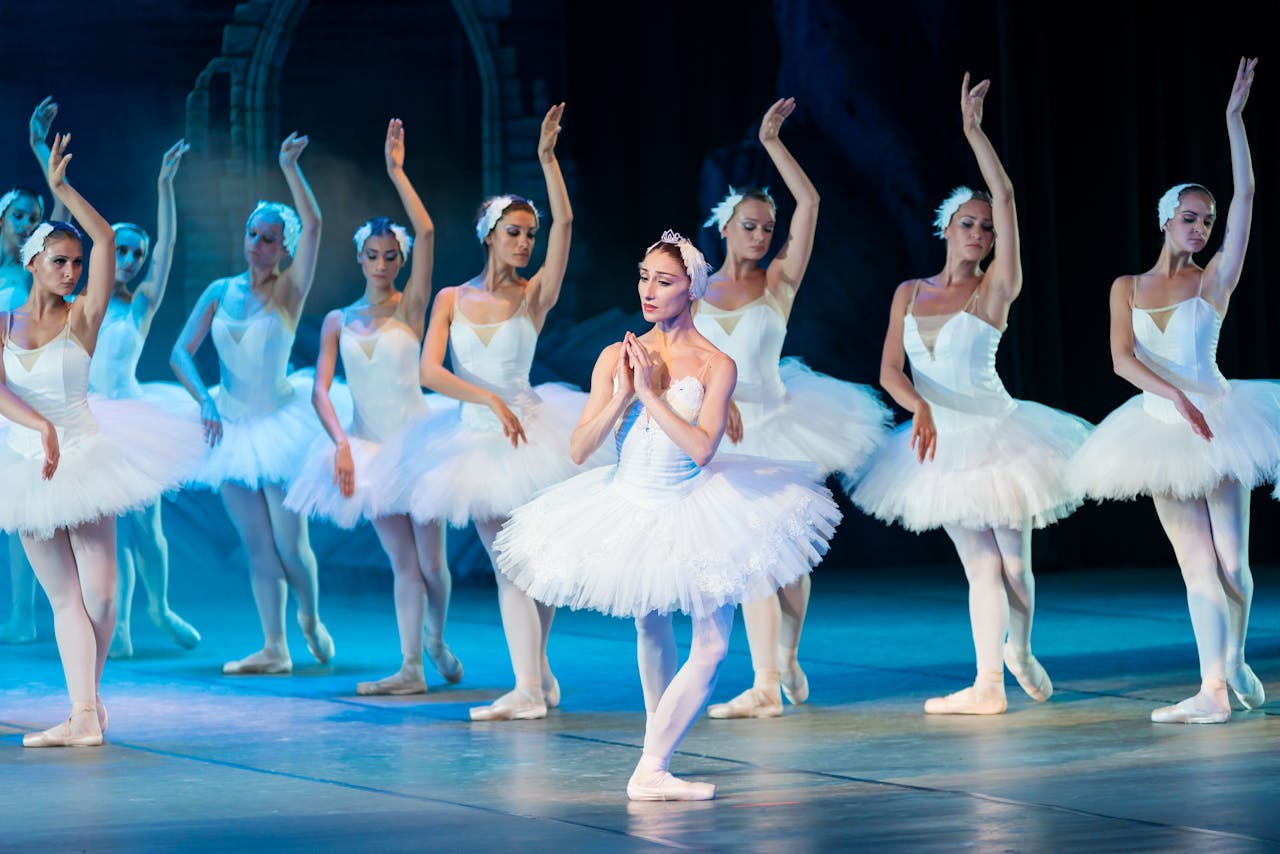 Ballerinas on stage in white tutus during performance.