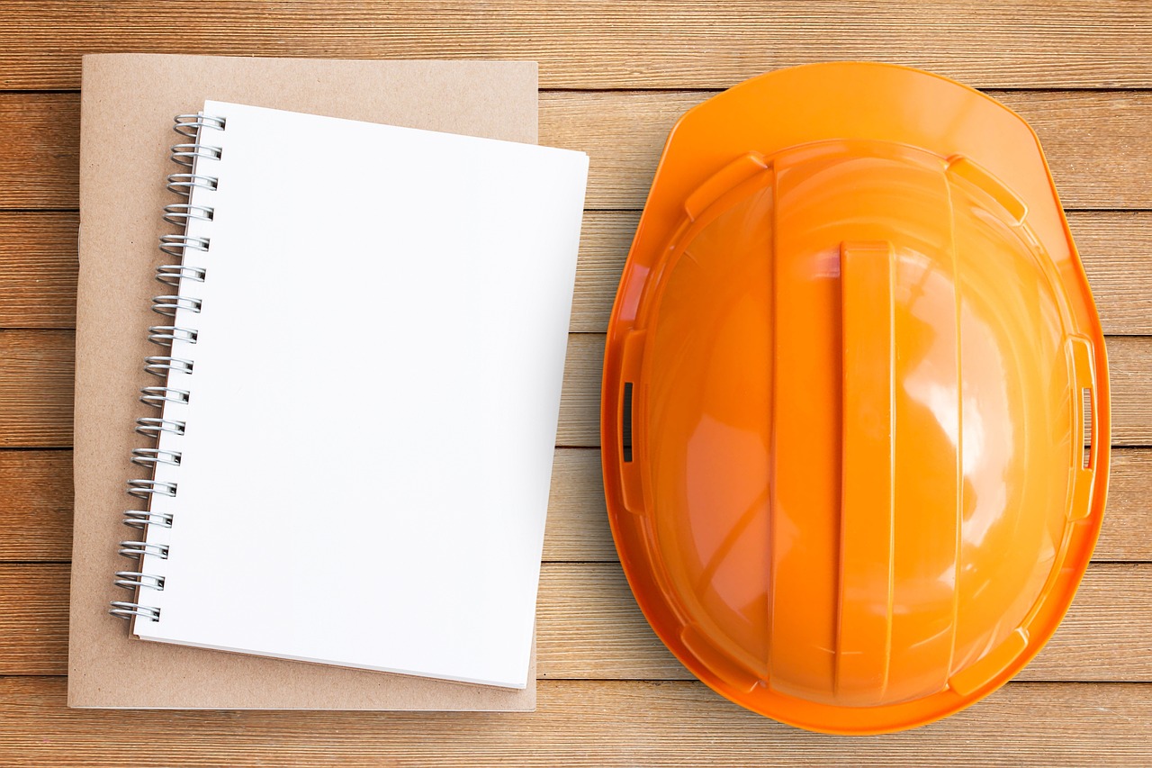 Orange construction helmet next to notepad.