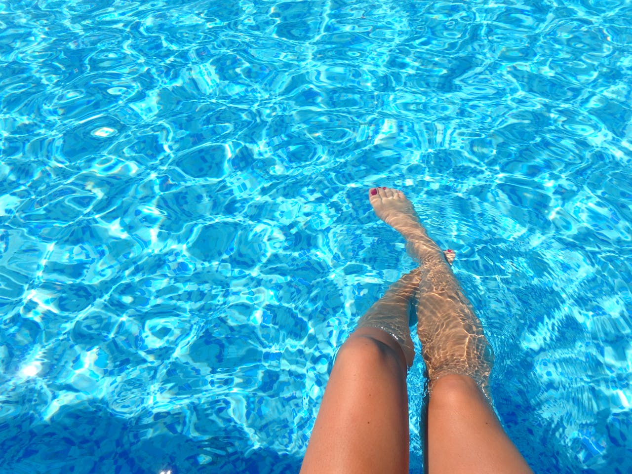 Woman with legs in swimming pool.