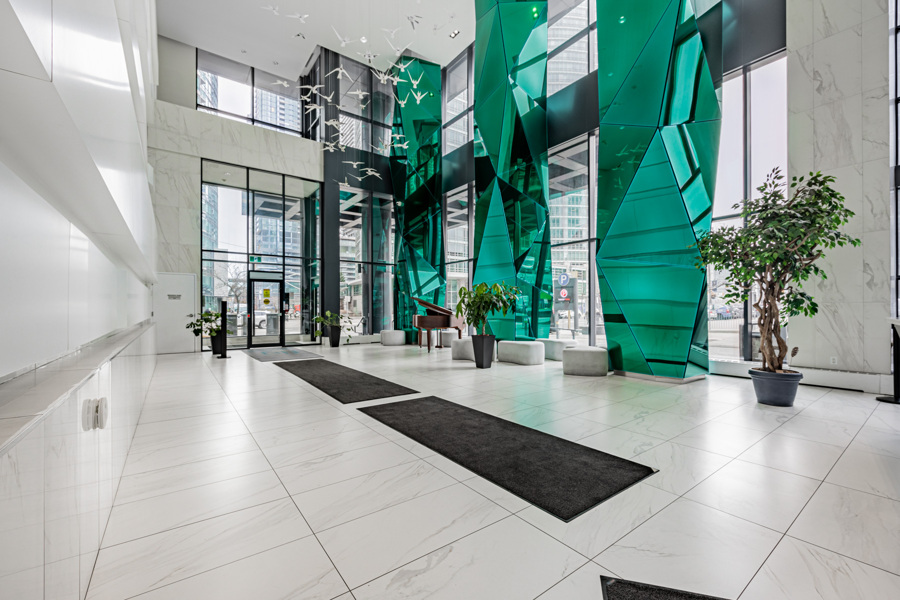 FLY Condos luxurious lobby with green glassy pillars and display of birds in midair.