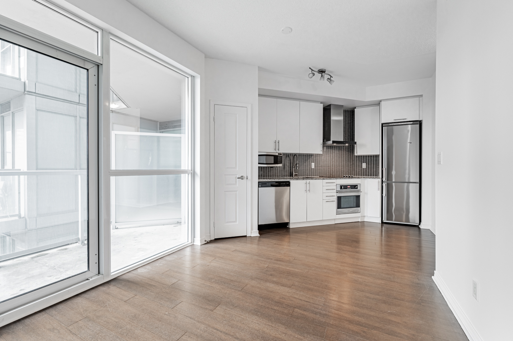 Living room, dining room and kitchen with dark laminate floors – 352 Front St W #1610.