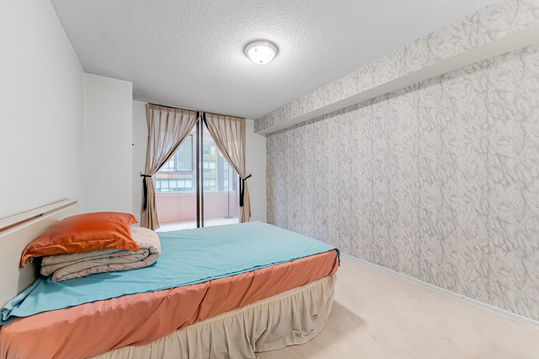 Condo bedroom with broadloom carpet and gray floral wallpaper.