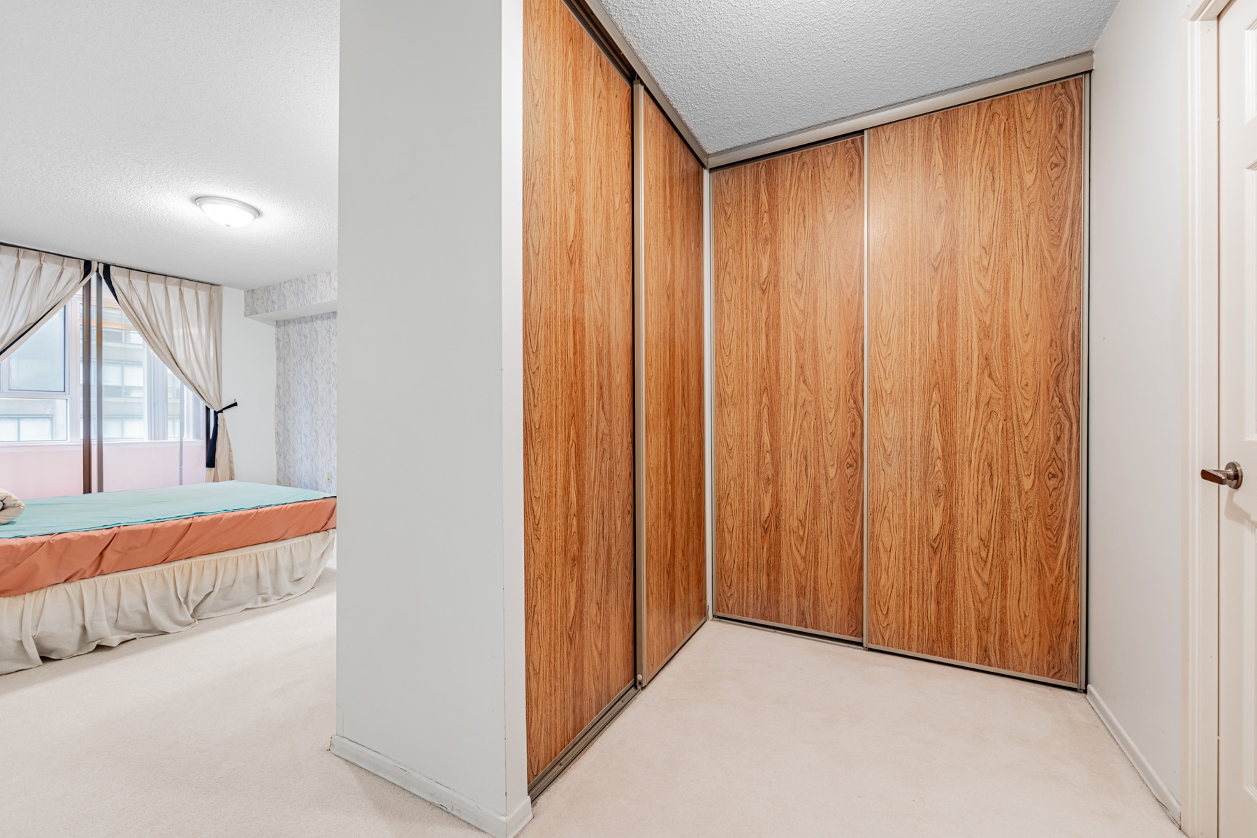 Wall-in closet with wood textured doors.