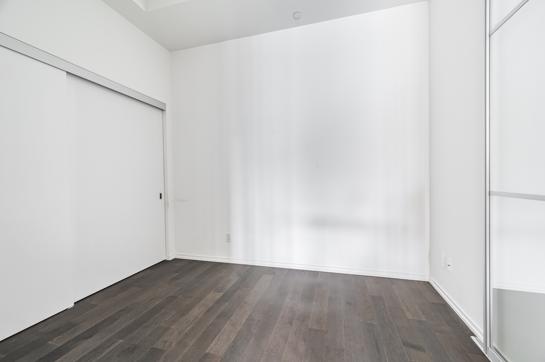 Empty bedroom with dark brown laminate floors.