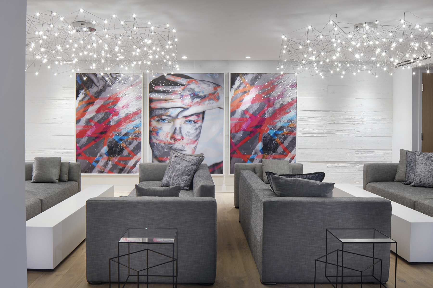 The Art Shoppe lounge with chic chandeliers, paintings and gray sofas.