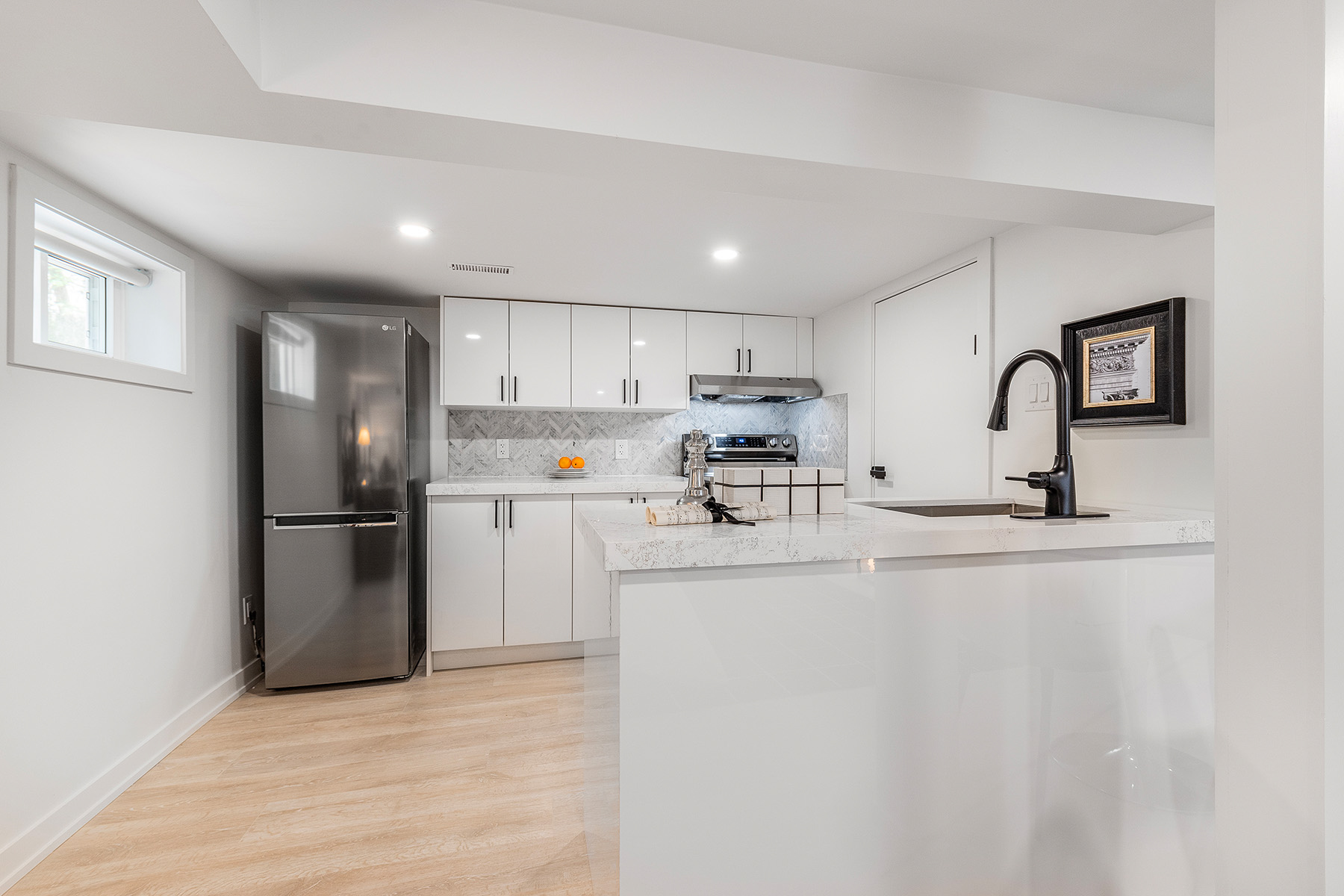 54 Huntington Avenue basement kitchen with shiny white cabinets, white quartz counters and LED lights.