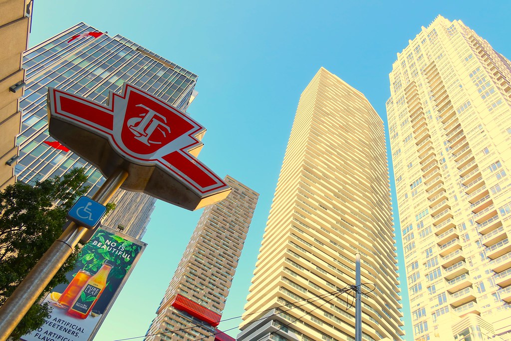 Looking up at TTC sign and buildings in Midtown Toronto.
