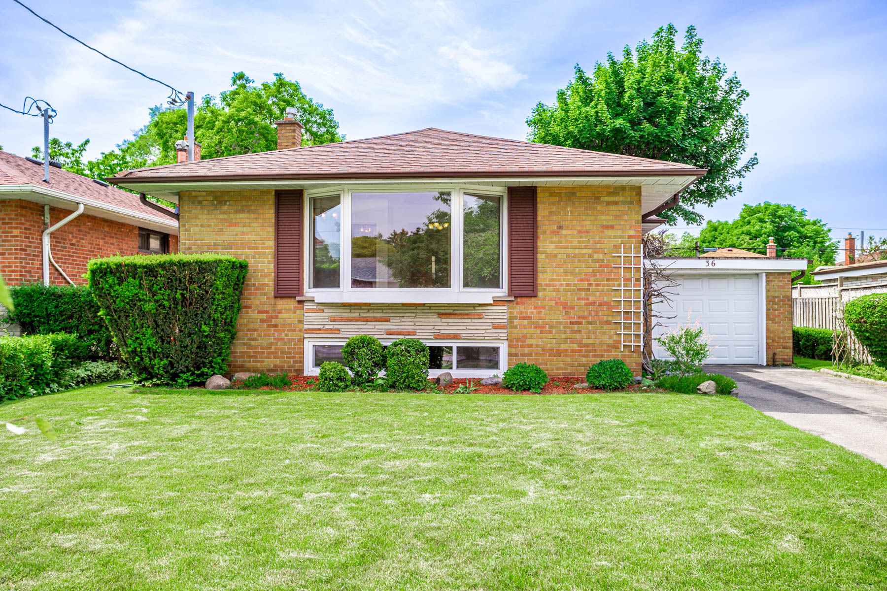 36 Earlton Rd, bungalow with red and brown bricks, large windows, and shingled roof.