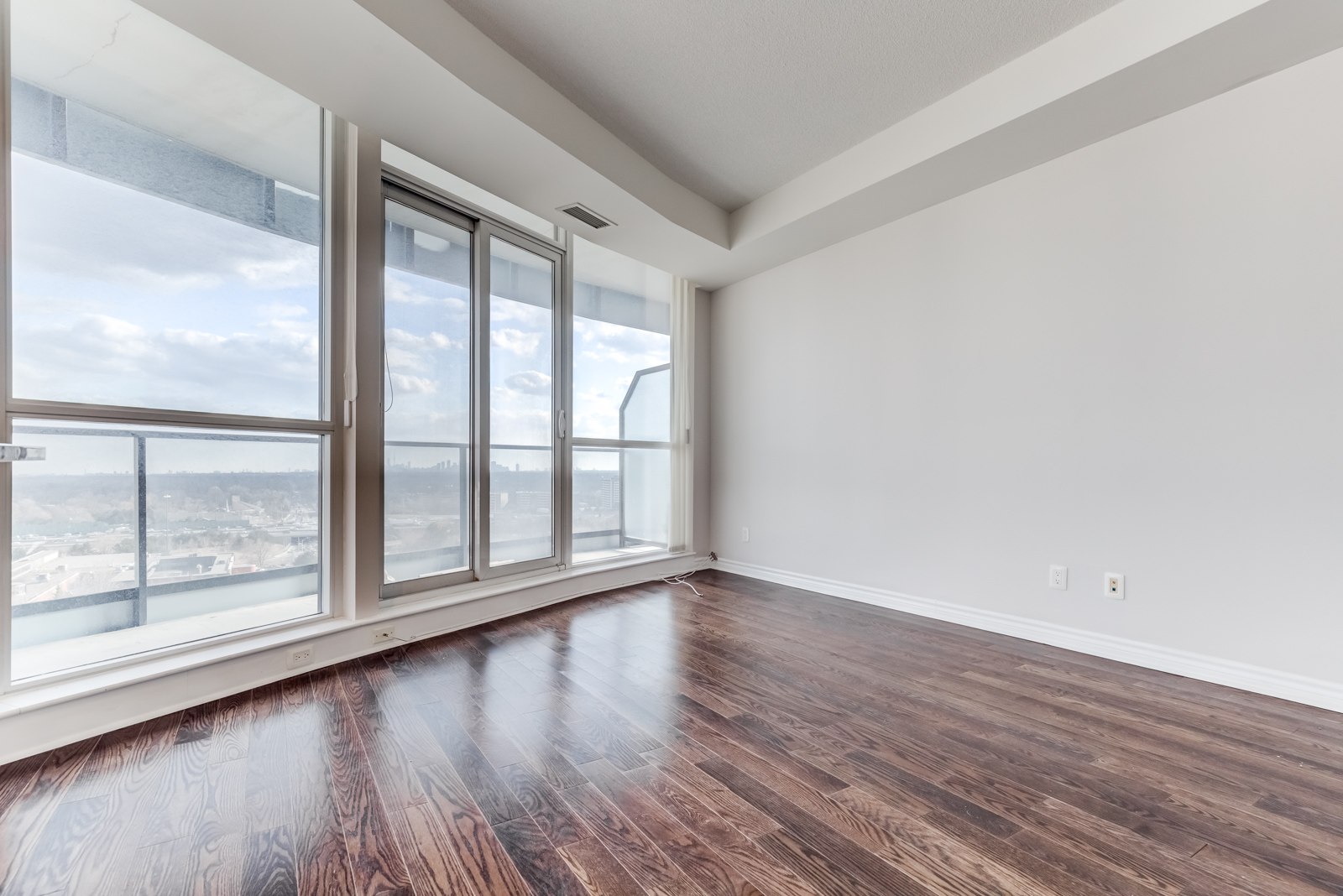 Dark brown hardwood floors and gray walls of condo living room.