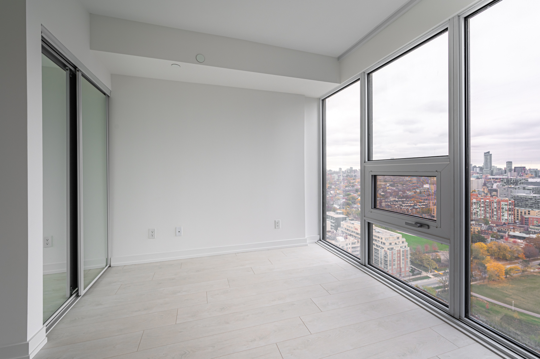 Condo bedroom with laminate floors and large windows.