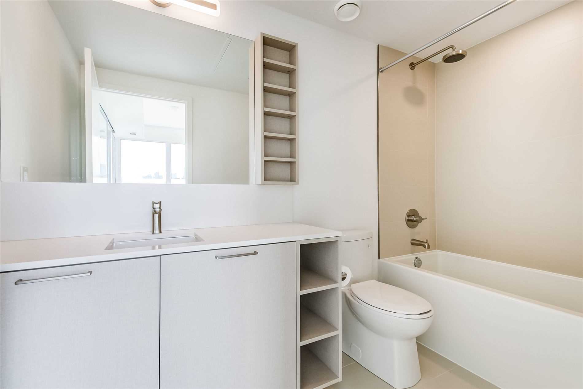 4-piece condo bathroom with built-in shelves, vanity, wall-mounted shelves, ceramic tiles, and soaker tub.