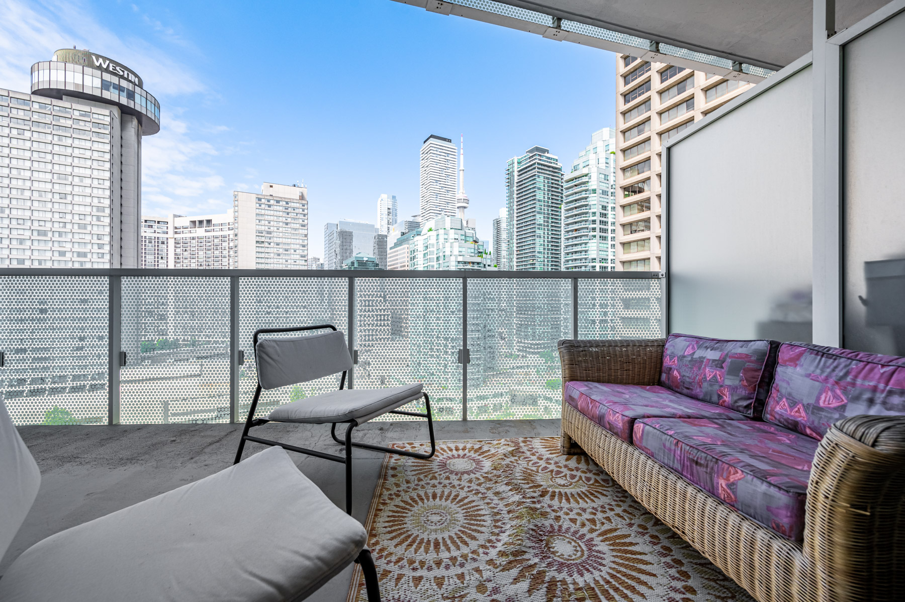 Spacious balcony of 15 Queens Quay E Unit 1405 with sofa, rug and chairs.