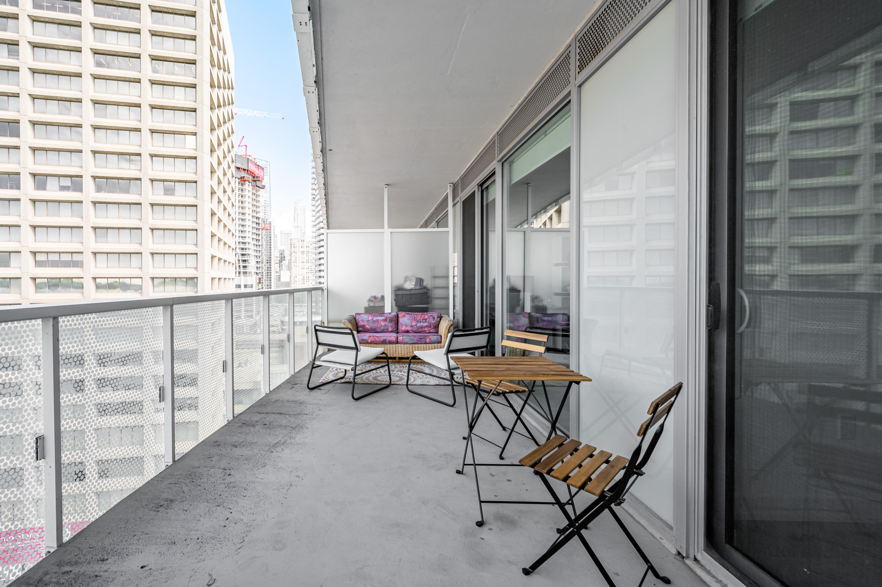 Large condo balcony looking sparse with furniture.