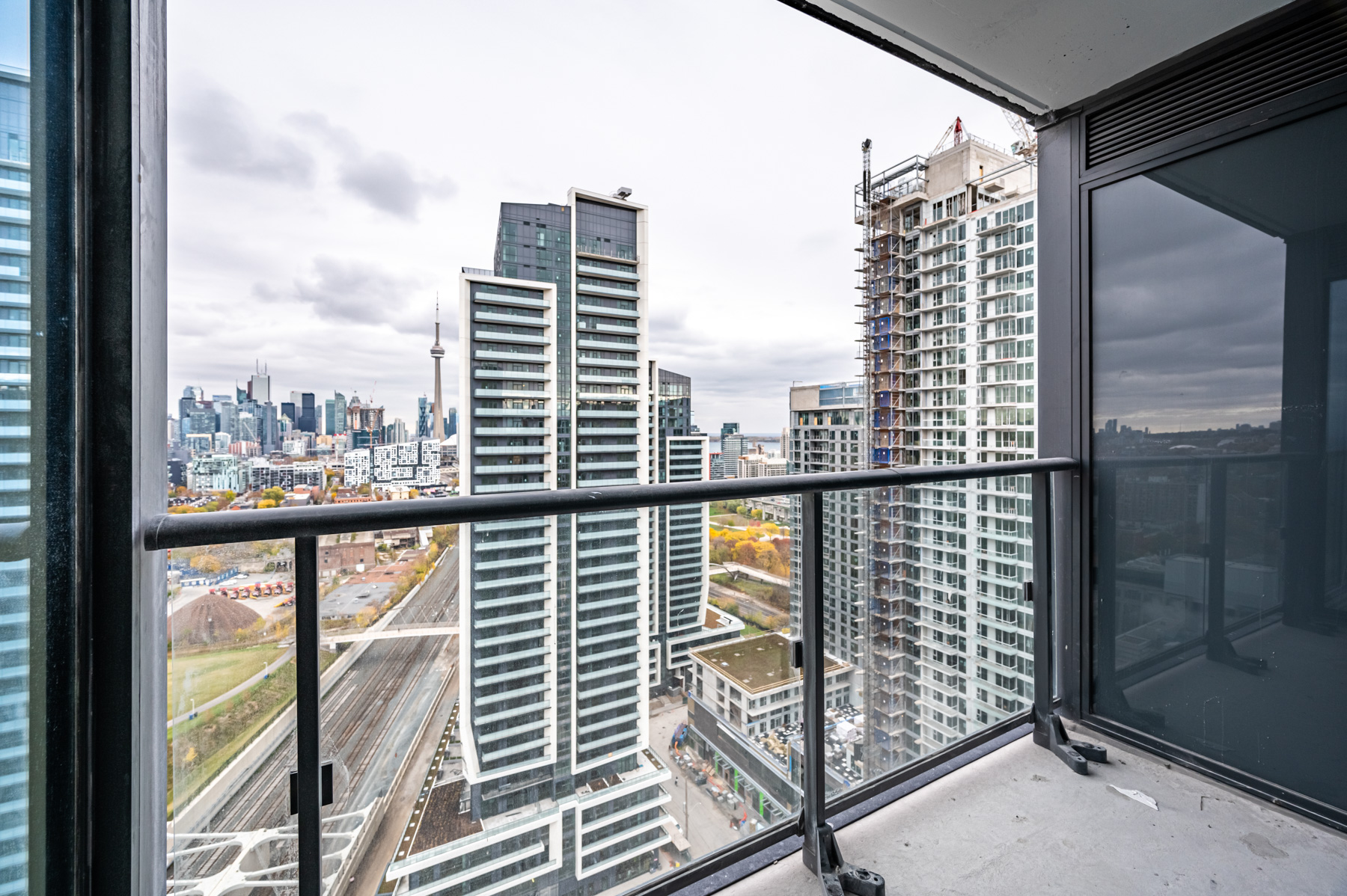 Condo balcony with glass panels and dark privacy screen.