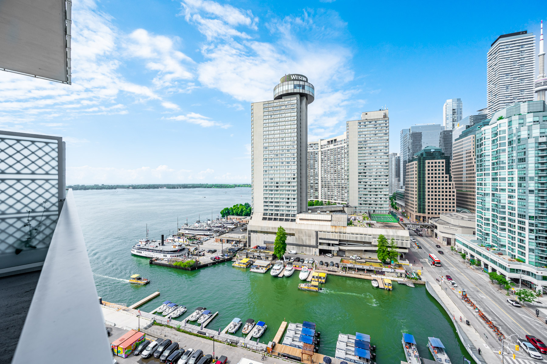 View of streets, cars, boats, buildings, buses, skies, trees and Lake Ontario from 15 Queens Quay E Unit 1405 balcony.