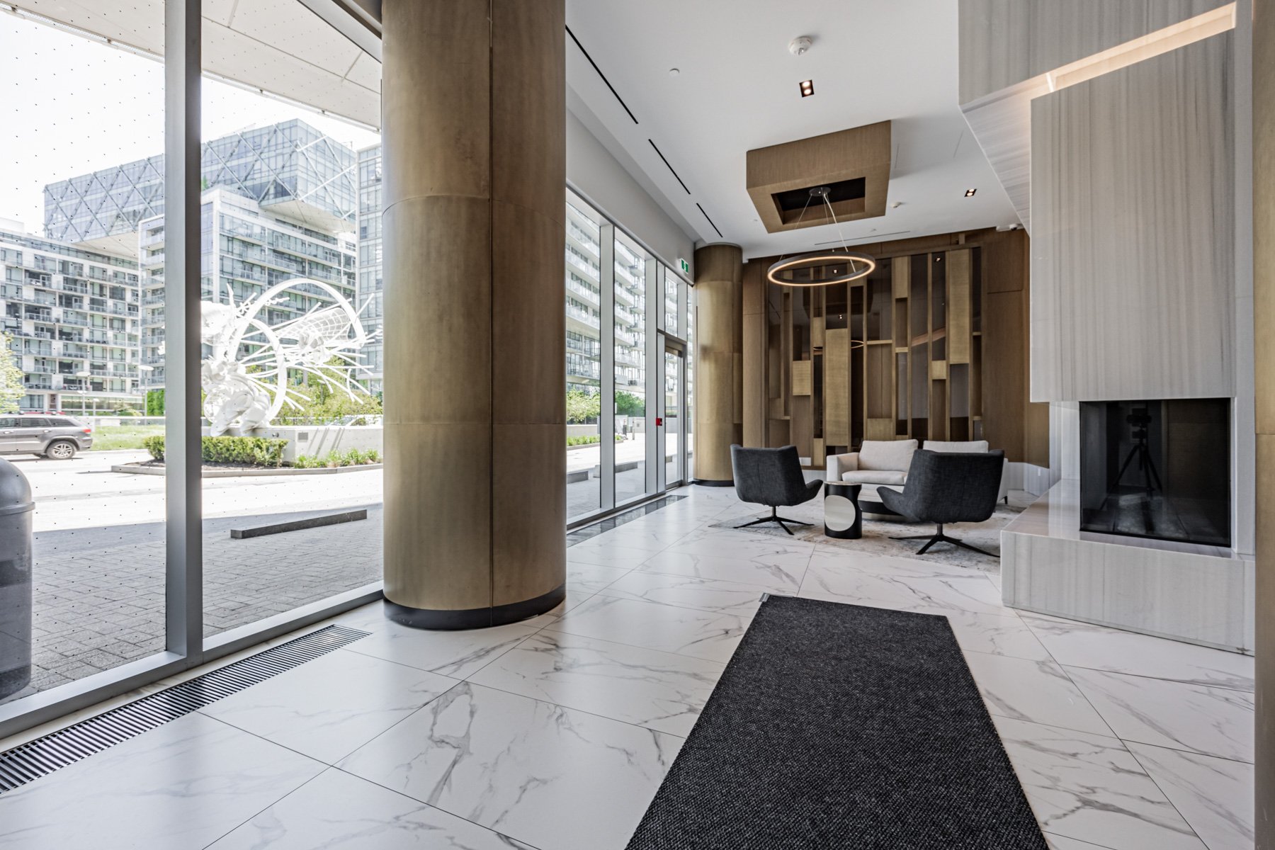 Condo lobby with fireplace, modern furniture and view of sculpture.