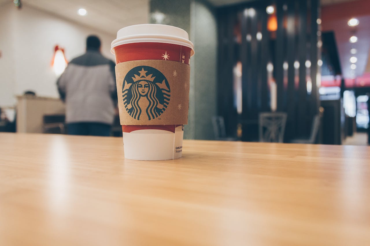 Starbucks cup in foreground with customer in background. 