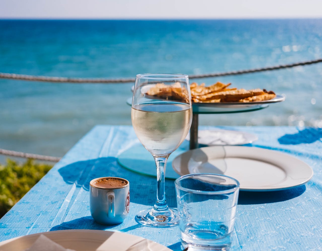 Dining table with plates, glasses, good, coffee in front of lake.