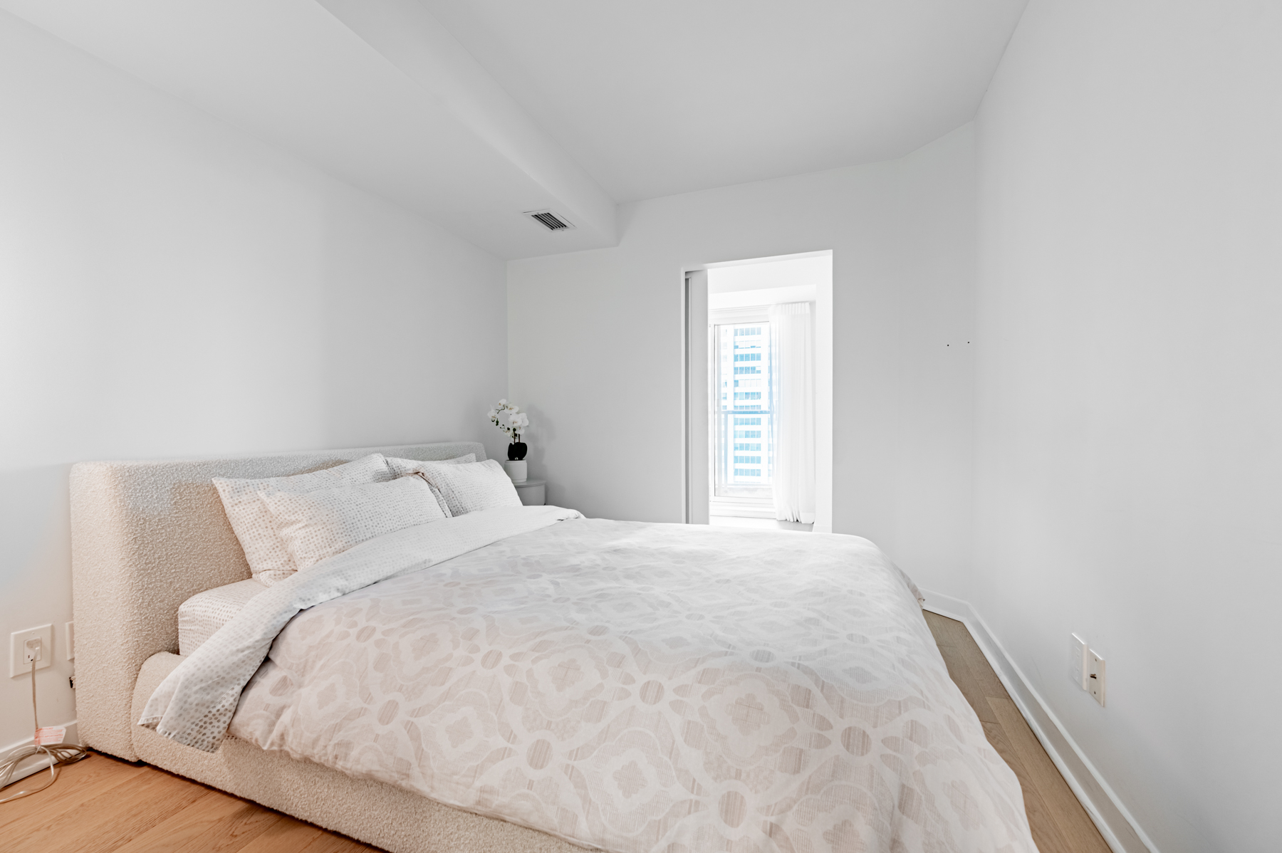 Condo bedroom lit by sunlight from den.