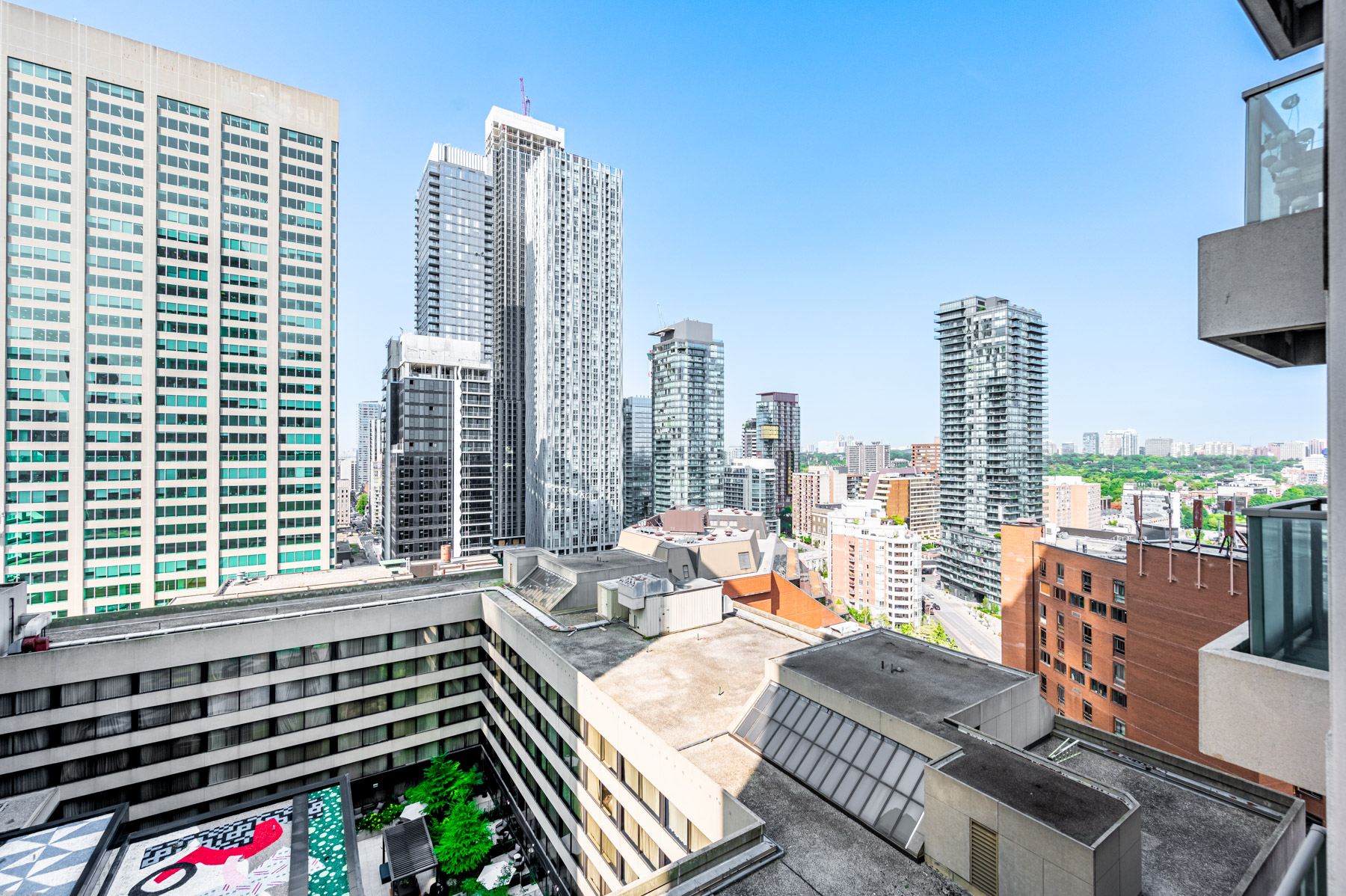 View of Toronto buildings, greenery and blue skies from balcony of 8 Park Rd Suite 2315.