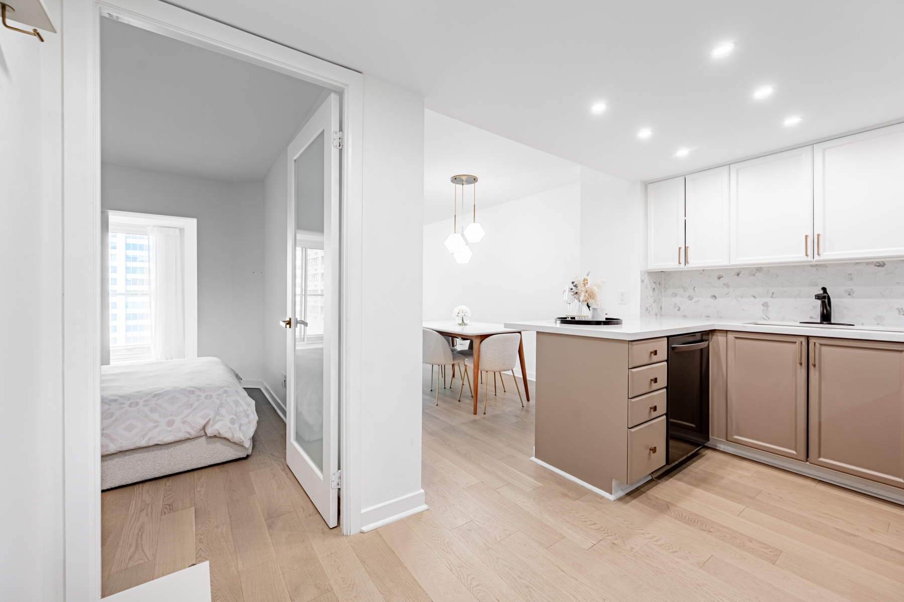 Condo kitchen with potlights and dining room with pendent lights.