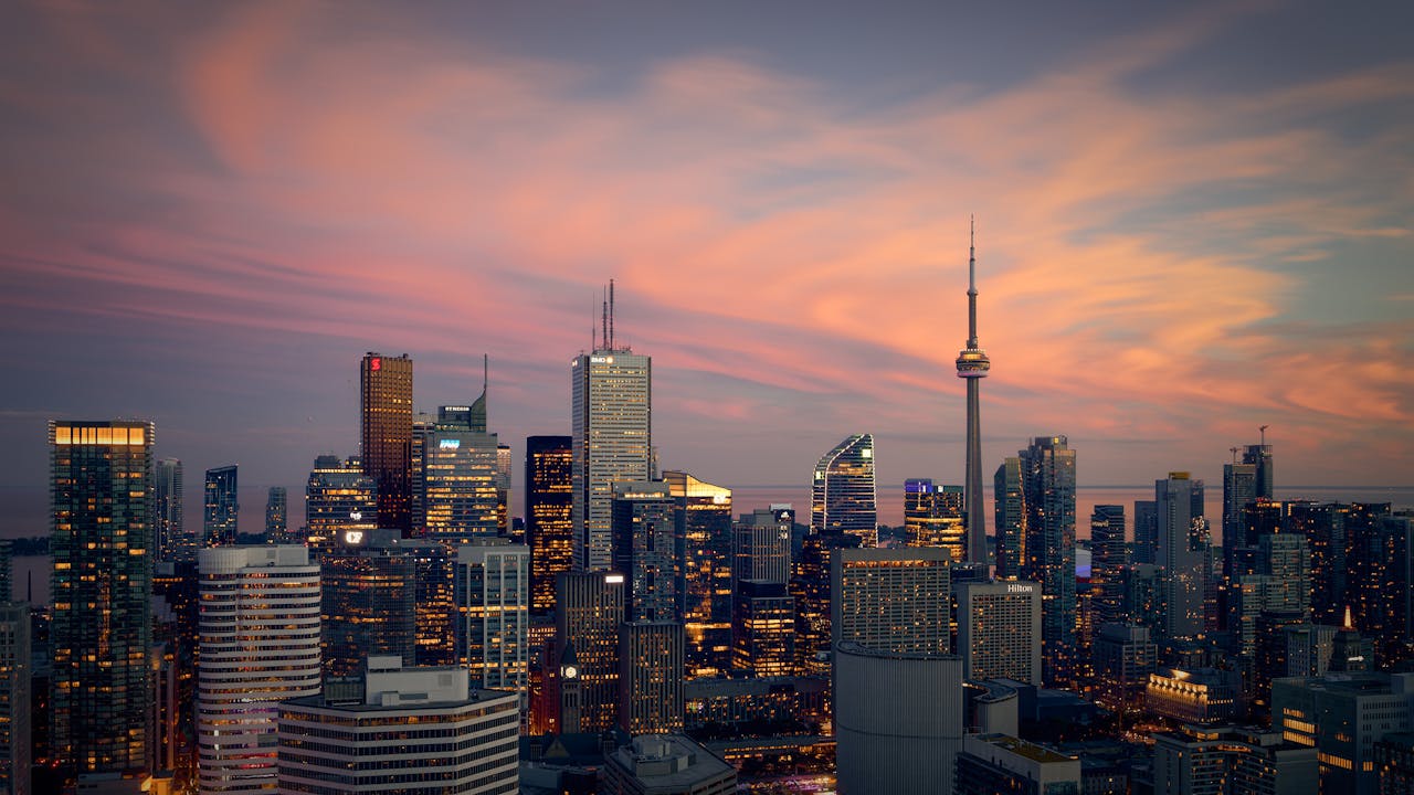 Photo of Toronto skyline at dusk with CN Tower and city lights.