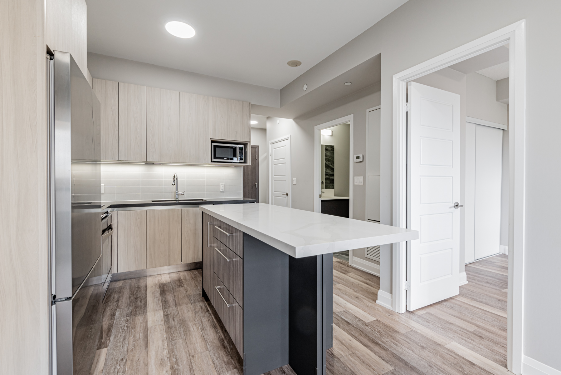 Condo kitchen with white quartz centre island – 711-15 Water Walk Dr.