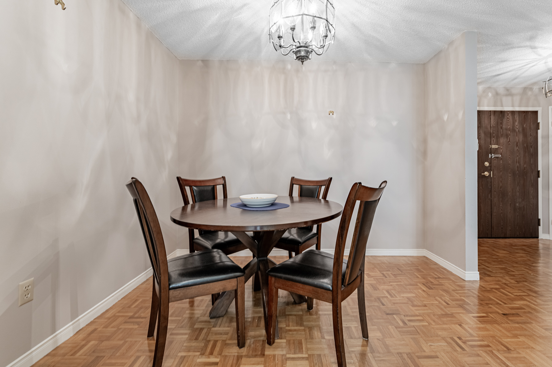 Condo dining room lit by silver chandelier. 