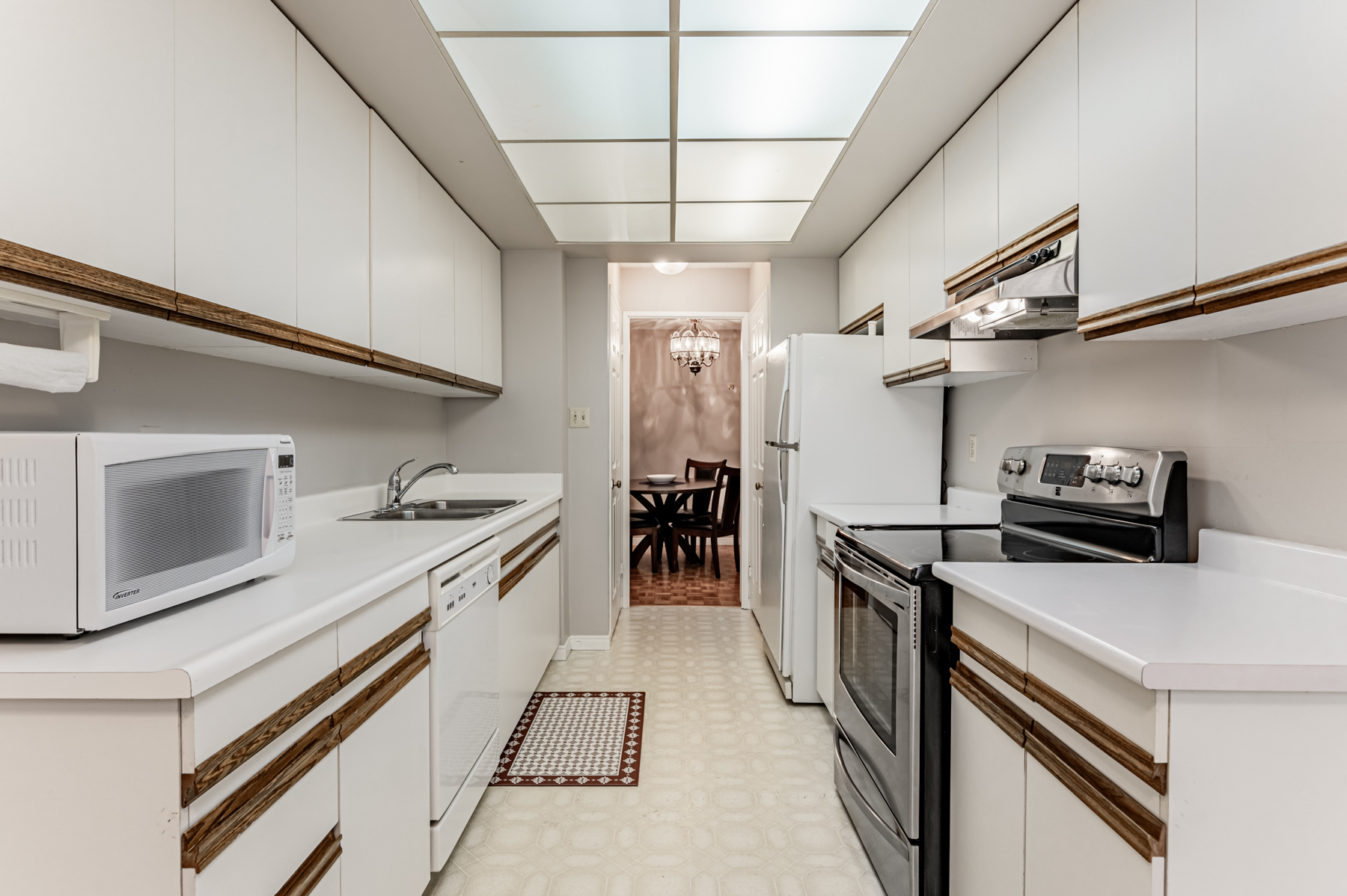 Condo kitchen with vinyl floors and fluorescent lights.