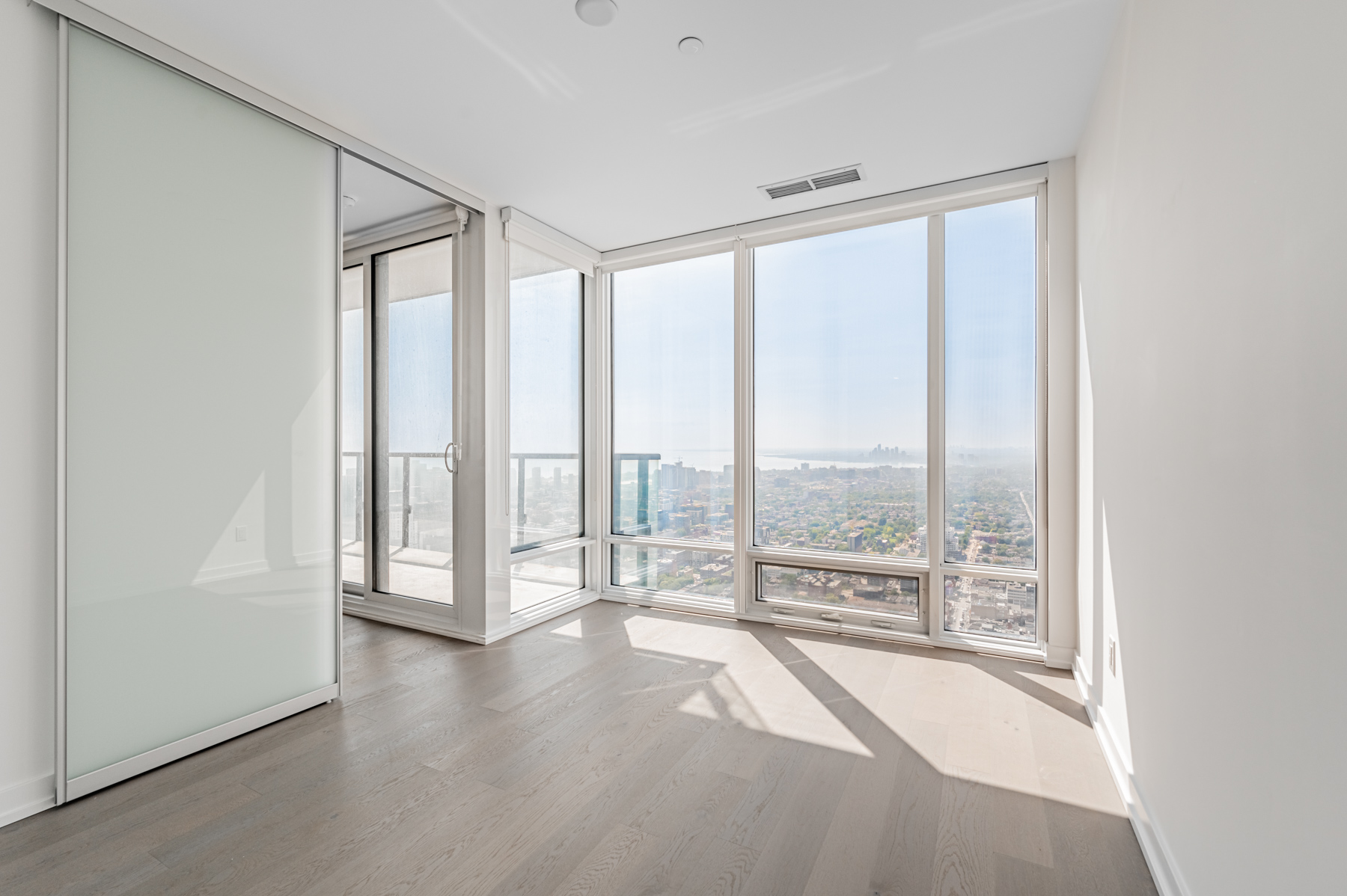 Condo bedroom with sliding doors and floor-to-ceiling windows.