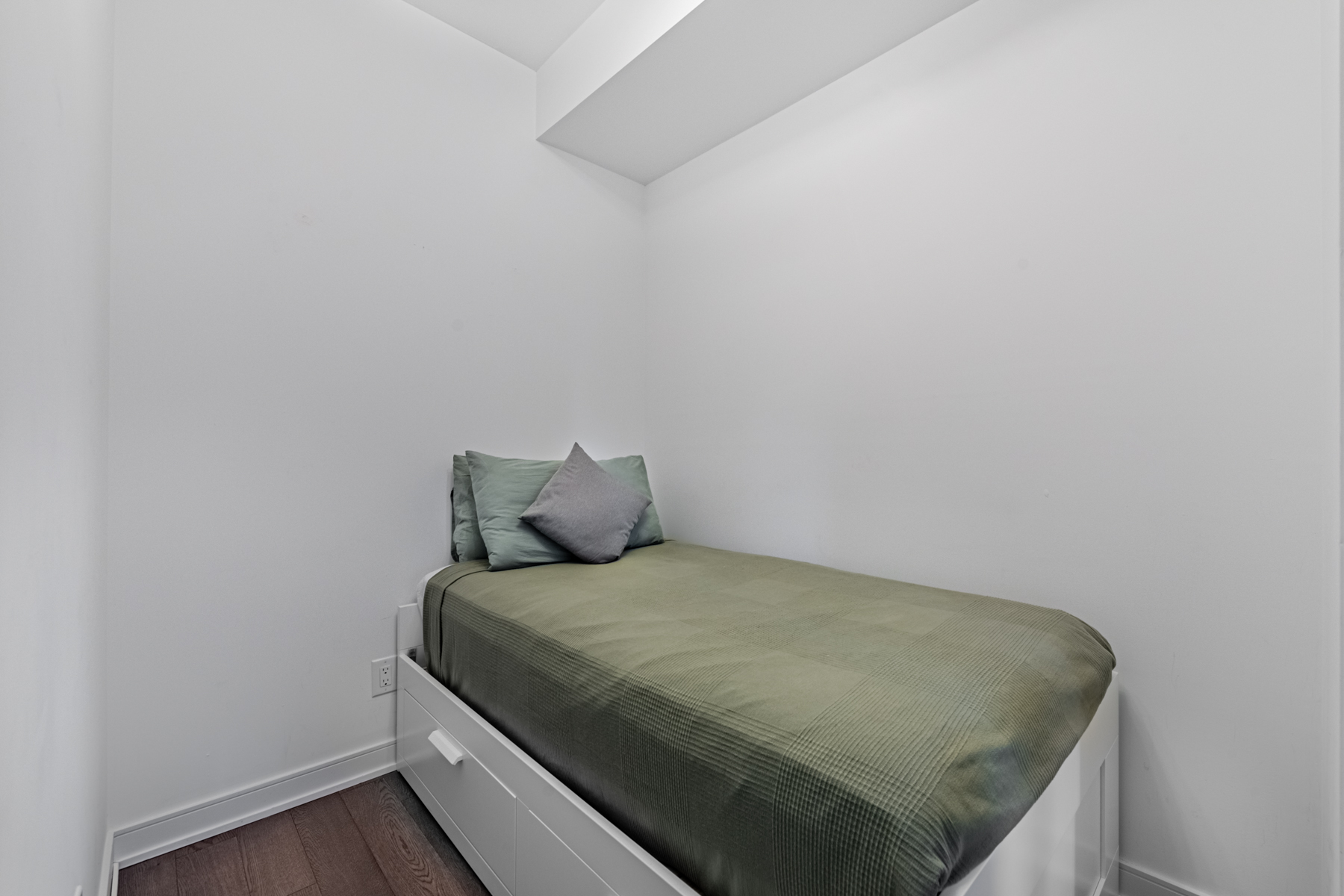 Condo bedroom with small green covered bed.