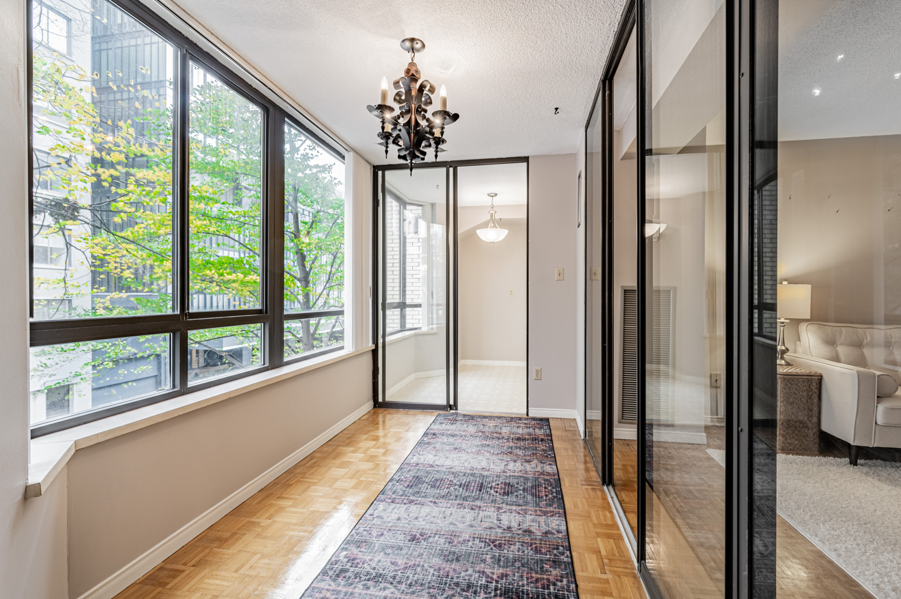 Condo solarium with parquet floors and black chandelier. 