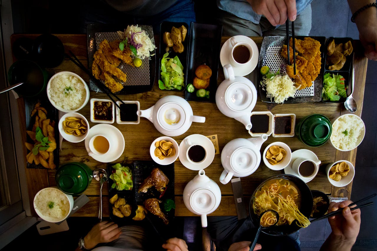 Looking down at restaurant table crowded with Chinese food. 