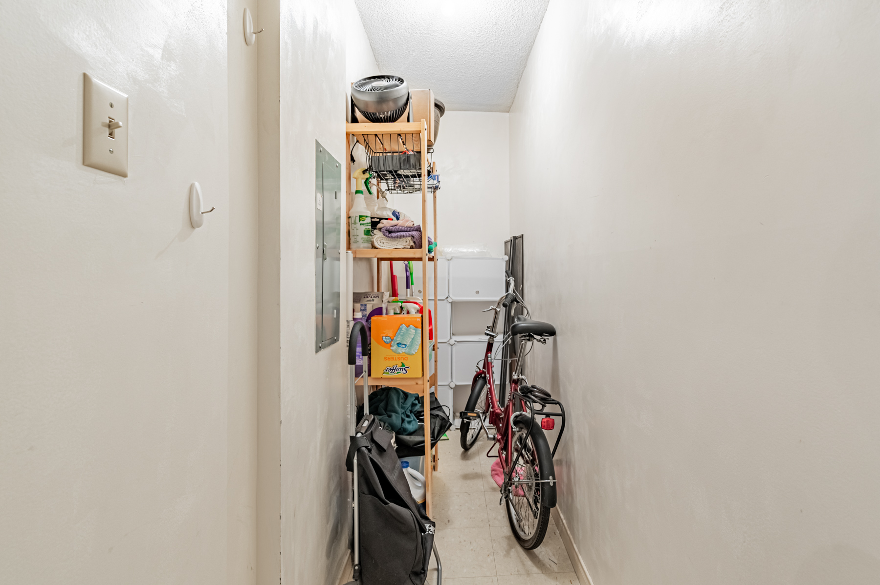 Narrow condo closet with bicycle and miscellaneous items.