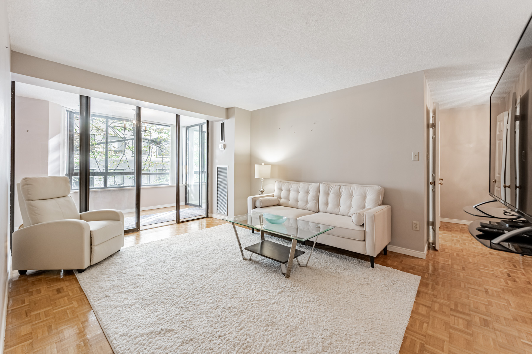 Condo living room with parquet flooring and carpet.